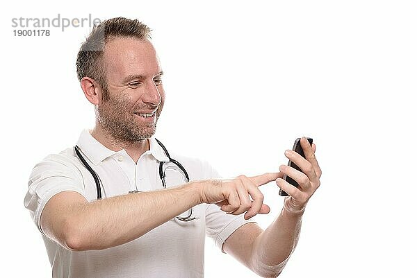 Lächelnder  unrasierter  glücklicher Arzt  der mit seinem Handy telefoniert  in der Erwartung  die gute Nachricht einer erfolgreichen Behandlung oder Diagnose mitzuteilen  vor weißem Hintergrund