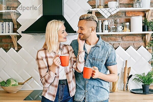 Junge glückliche Paar in der Liebe trinken Kaffee am Morgen umarmt in der Küche zu Hause. Beziehung  Familie Konzept