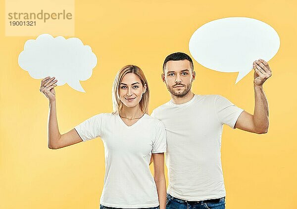 Lächelnde Frau und Mann halten Papier Gedankenblasen über gelben Hintergrund. Beziehung Konzept