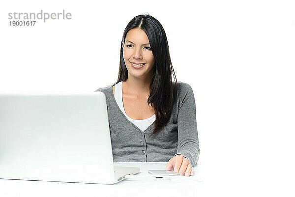 Frau sitzt konzentriert und schaut auf ihren Laptop mit angeschlossener externer Festplatte und ruhigem Lächeln  vor weißem Hintergrund