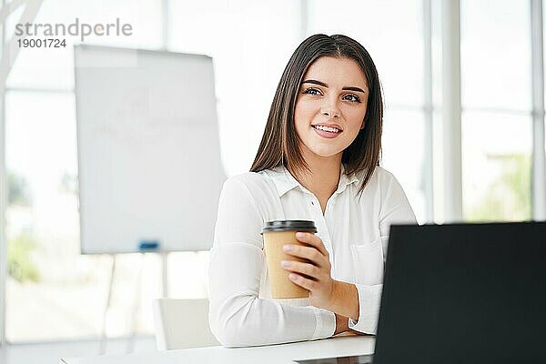 Hübsche Geschäftsfrau mit Tasse Kaffee entspannen während der Pause in modernen kreativen Büro mit Kopie Raum. Entspannen  Erfolg Konzept