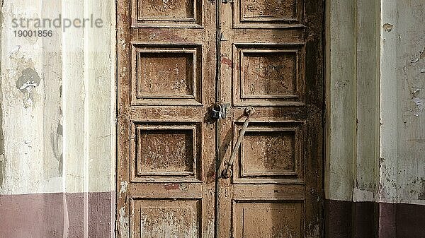 Verlassene alte Tür mit Schloss. Rost auf dem Metallschloss. Abblätternde braune Farbe an der alten Tür