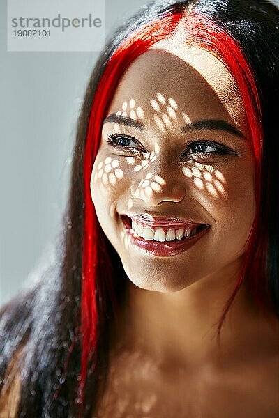 Porträt der lächelnden hübschen afroamerikanischen Frau mit Schatten auf ihrem Gesicht. Modekonzept weibliche Schönheit