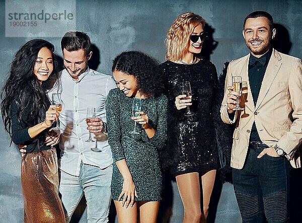 Eine bunte Gruppe von Menschen genießt die Party und hat Spaß Junge Freunde trinken Champagner und hängen im Nachtclub ab