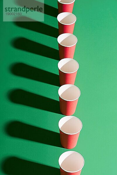 Draufsicht auf roten Pappbecher in Reihe auf grünem Hintergrund mit Schatten. kreatives Konzept  minimalistisch  moderne Kunst