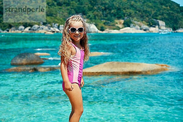 Süßes kleines Mädchen in Sonnenbrille posiert auf schönen tropischen Strand. Sommer  Spaß und Urlaub Konzept
