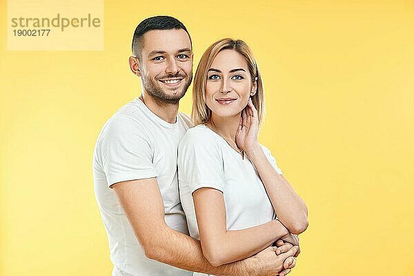 Junges glückliches Paar  das sich auf gelbem Hintergrund umarmt. Beziehung Konzept