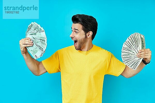 Glücklich aufgeregt Mann hält Geld Banknoten auf blauem Hintergrund. Geschäft  Gewinn  Einkommen  Erfolg Konzept
