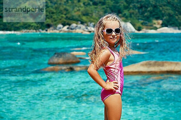 Süßes kleines Mädchen in Sonnenbrille posiert auf schönen tropischen Strand. Sommer  Spaß und Urlaub Konzept