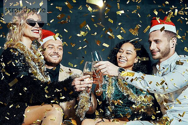 Multiethnische glückliche Freunde stoßen mit Champagner an  feiern Weihnachten oder Neujahr  gratulieren sich gegenseitig und genießen die Party. Feiern und Prost Konzept
