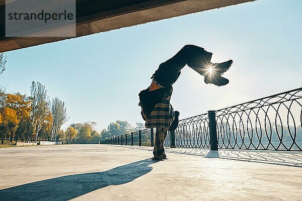 Junger Mann Breakdancer tanzt auf städtischen Hintergrund Durchführung akrobatische Stunts. Straßenkünstler Breakdance im Freien