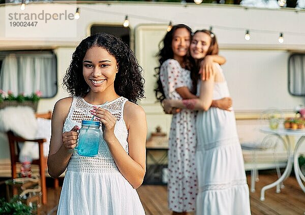 Schöne afrikanische Amerikanerin Porträt während Picknick neben ihrem Wohnmobil und Freunde auf dem Hintergrund. Urlaub  Reise und Urlaub Konzept