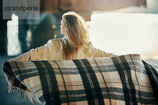 Rückenansicht der jungen Frau mit Decke genießen windigen sonnigen Tag posiert auf städtischen Straße Hintergrund. Freiheit Konzept