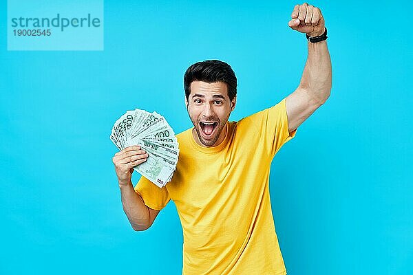 Glücklich aufgeregt Mann hält Stapel von Geld auf blauem Hintergrund. Geschäft  Gewinn  Einkommen  Erfolg Konzept
