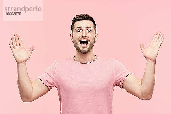Überrascht aufgeregt Mann Porträt mit erhobenen Armen über rosa Hintergrund. Emotionen  Erfolg  Gewinner Konzept