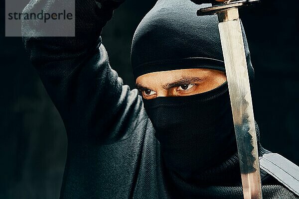 Kämpfende Ninja posiert mit einem Schwert über schwarzem Hintergrund. japanischen Kämpfer Konzept