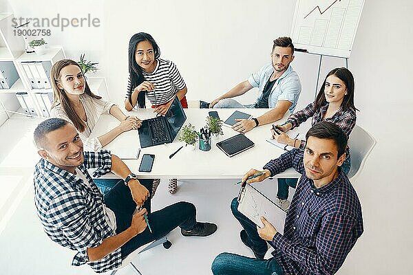 Lächelnde Gruppe junger Leute  die in einem kreativen Büro zusammenarbeiten und kommunizieren. Meeting  Teamworkkonzept erfolgreiches Team