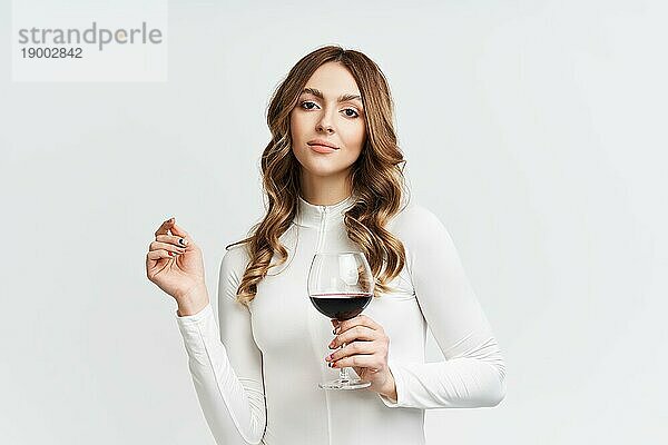 Pretty Mode Frau hält Glas Rotwein auf weißem Hintergrund. Entspannen  Feier Konzept