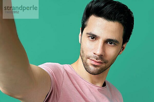 Close up Porträt von gut aussehend Mann nimmt selfie über blaün Hintergrund
