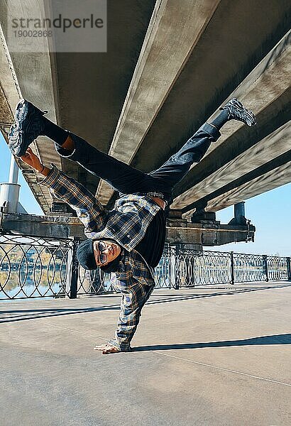 Junger Mann Breakdancer tanzt auf städtischen Hintergrund Durchführung akrobatische Stunts. Straßenkünstler Breakdance im Freien