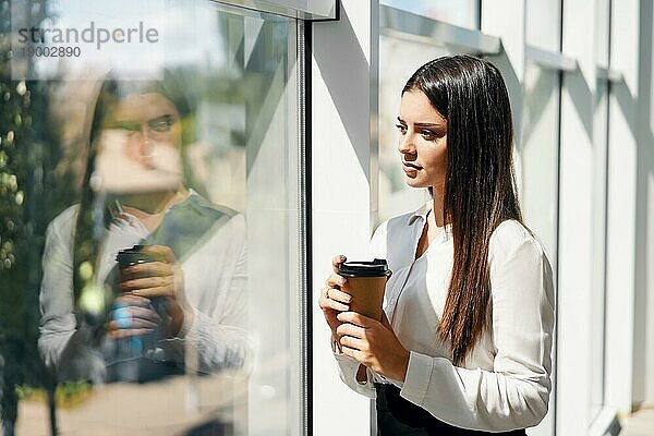 Porträt eines eleganten Geschäftsmannes mit einer Tasse Kaffee in der Hand während der Pause in einem modernen kreativen Büro mit Kopierraum. Entspannen  Erfolg Konzept