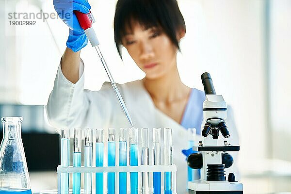 Asiatischer Wissenschaftler  der in einem großen modernen Labor arbeitet und forscht. Medizin  Mikrobiologie  Biotechnologie Konzept