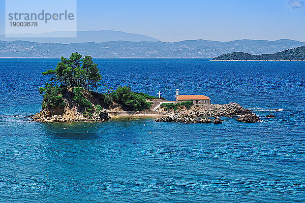 Kleine christliche Kirchenkapelle aus Stein mit Kreuz auf einem kleinen Inselstreifen in ruhiger See  griechische Inseln  Griechenland  Europa
