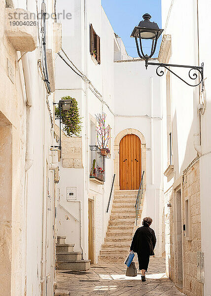 Frau geht in einer engen Straße in der Altstadt  Locorotondu  Apulien  Italien  Europa