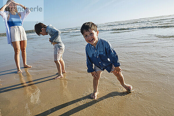 Lächelnder Junge  der mit der Familie am Strand genießt
