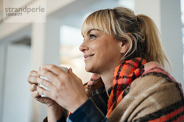 Lächelnde blonde Frau mit Kaffeetasse