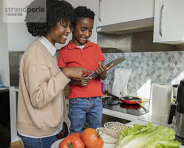 Glückliche Mutter und Sohn nutzen Tablet-PC in der heimischen Küche