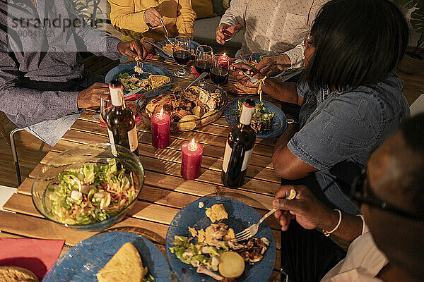 Multikulturelle ältere Freunde bei Essen und Wein mit Kerzen auf dem Esstisch