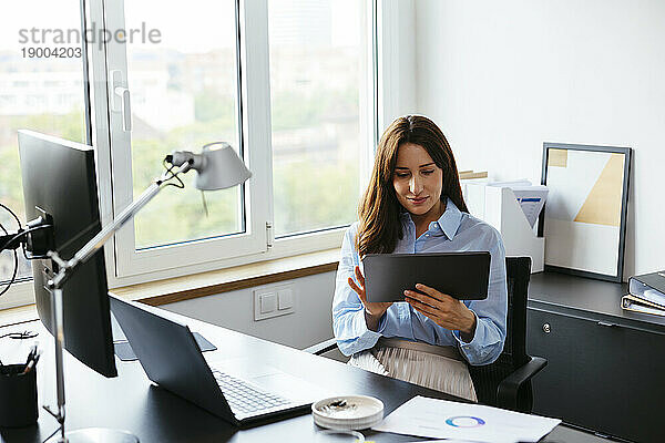 Geschäftsfrau nutzt Tablet-PC am Schreibtisch im Büro