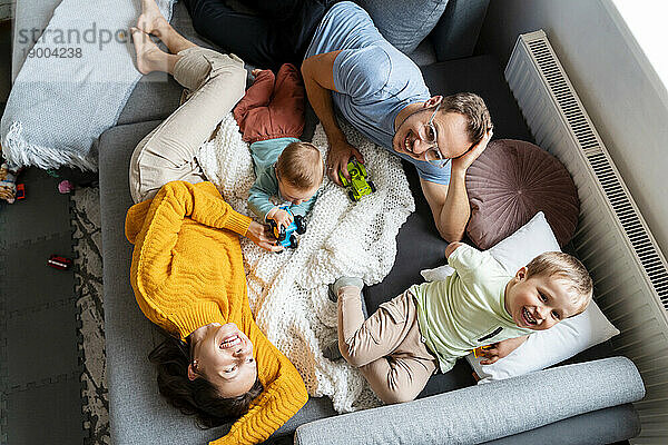 Eltern verbringen ihre Freizeit mit Kindern  die zu Hause auf der Couch spielen