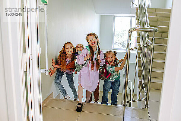 Cheerful schoolgirls standing on stairs at break time
