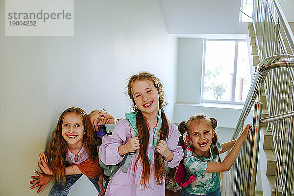 Happy schoolgirls standing on stairs at break time