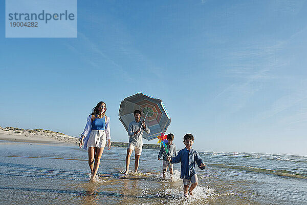 Glückliche Familie  die an einem sonnigen Tag am Strand spaziert