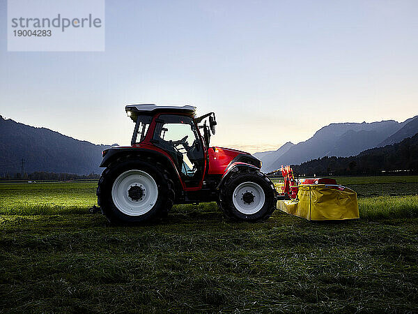 Traktor auf Rasenfläche in der Abenddämmerung