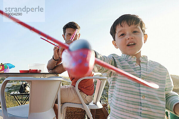 Junge spielt an sonnigem Tag mit Spielzeugflugzeug