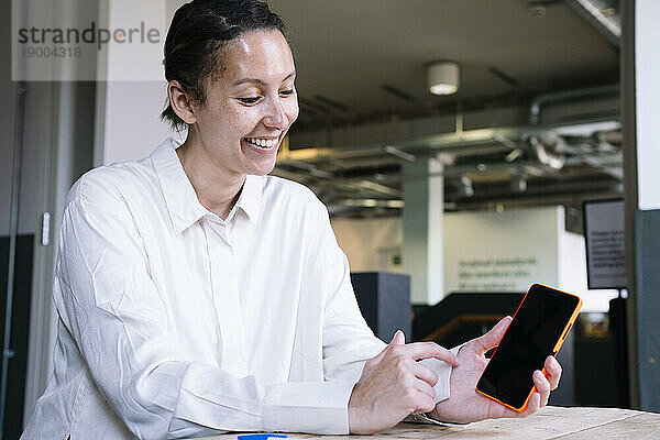 Lächelnde Geschäftsfrau zeigt Smartphone