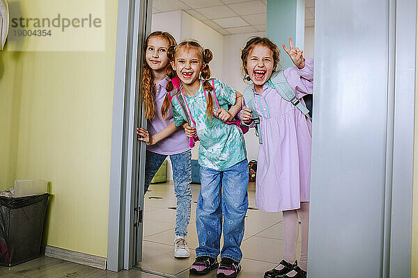 Smiling schoolgirls standing in classroom doorway
