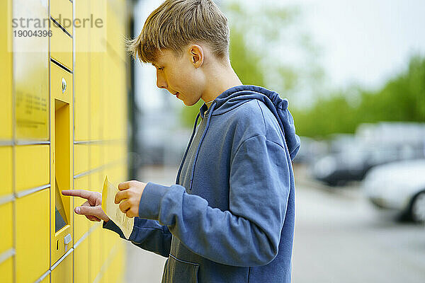 Junge mit Ticket gibt Daten in Paketschließfachautomat ein