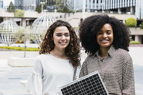 Glückliche Geschäftsfrauen stehen mit Solarpanel