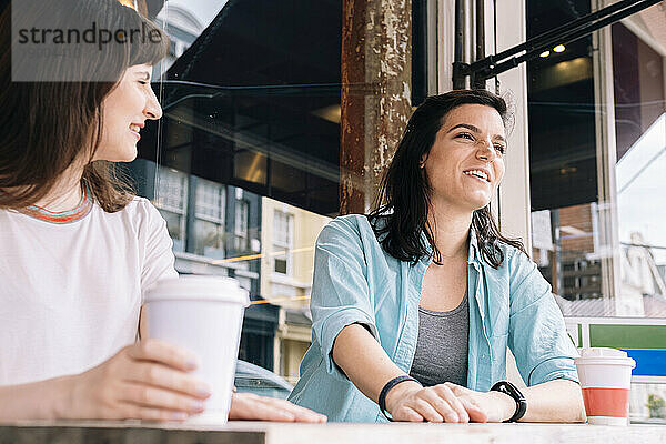 Lächelnde Freunde beim Kaffee im Straßencafé