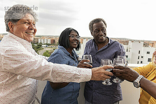 Glückliche ältere Freunde  die gemeinsam Wein auf dem Balkon genießen