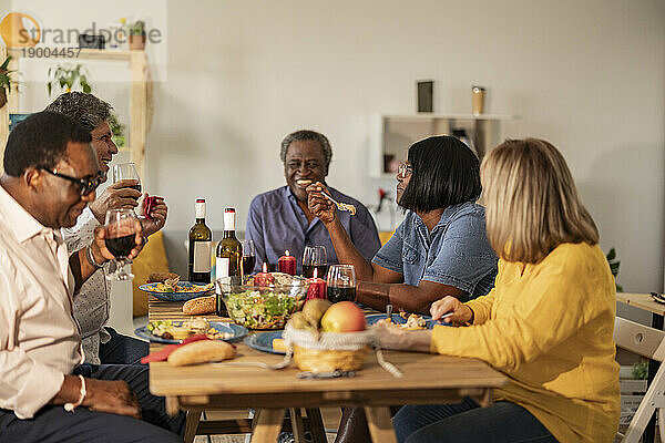 Fröhliche ältere multikulturelle Freunde beim Essen auf einer Dinnerparty