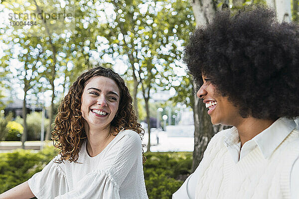 Smiling curly haired woman spending time with friend