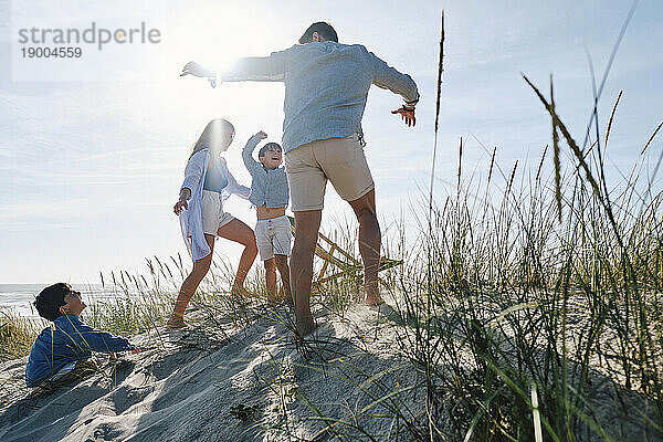 Eltern spielen an einem sonnigen Tag mit Kindern am Strand