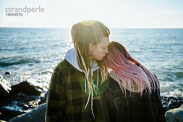 Liebevolles lesbisches Paar  das am Meer steht