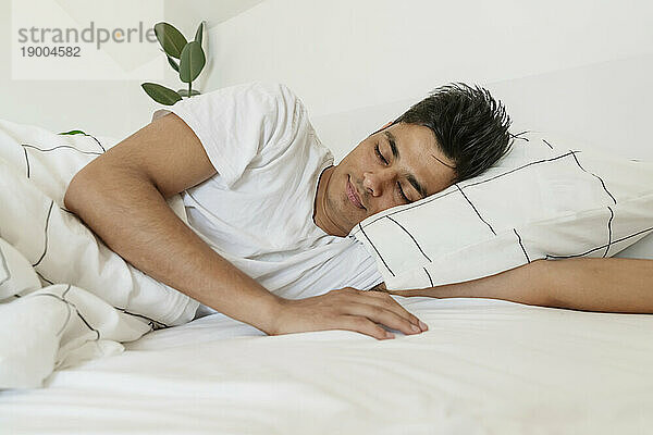 Young man taking nap on bed at home